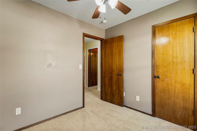 unfurnished bedroom with carpet flooring, a textured ceiling, baseboards, and ceiling fan