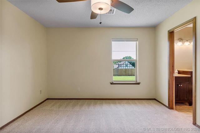 empty room with light carpet, ceiling fan, a textured ceiling, and baseboards