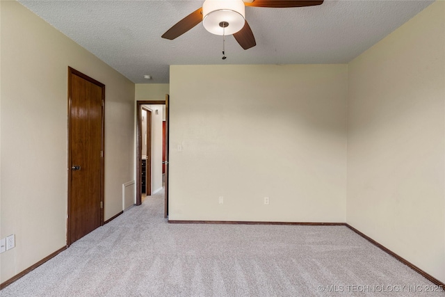 carpeted empty room with a ceiling fan, a textured ceiling, and baseboards