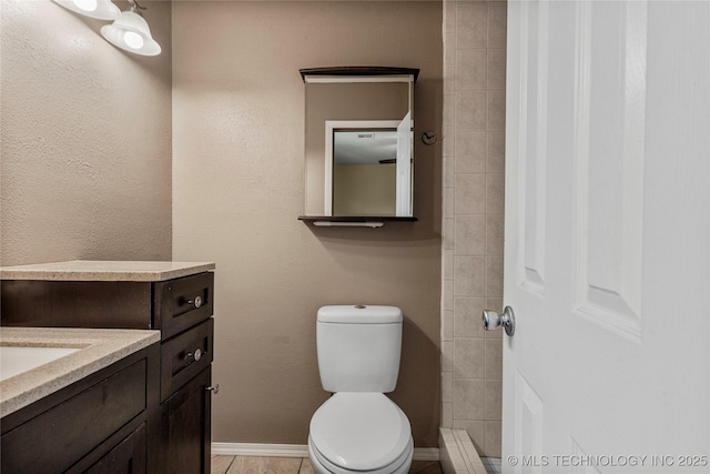 bathroom featuring vanity, toilet, and baseboards