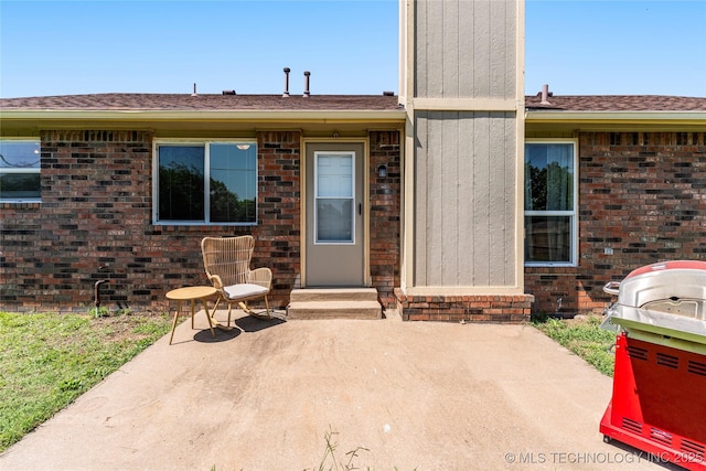 entrance to property with a patio and brick siding