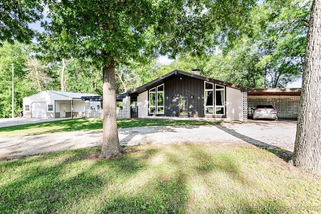 1300 S Mississippi, Ada, OK 74820 - mid-century home with a front lawn, board and batten siding, a chimney, and an attached carport