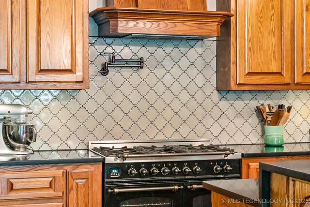1300 S Mississippi, Ada, OK 74820 - kitchen with range with two ovens, backsplash, brown cabinetry, and premium range hood