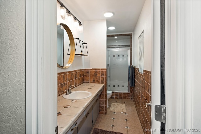 1300 S Mississippi, Ada, OK 74820 - bathroom with tile walls, toilet, a stall shower, vanity, and tile patterned floors