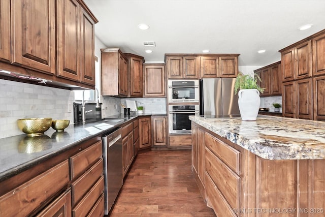 15209 S 89th W Ave, Sapulpa, OK 74066 - kitchen featuring appliances with stainless steel finishes, recessed lighting, dark wood-style floors, decorative backsplash, and dark stone counters