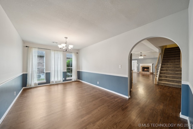 408 S Tamarack Ave, Broken Arrow, OK 74012 - spare room featuring a fireplace, dark wood finished floors, a chandelier, arched walkways, and stairs