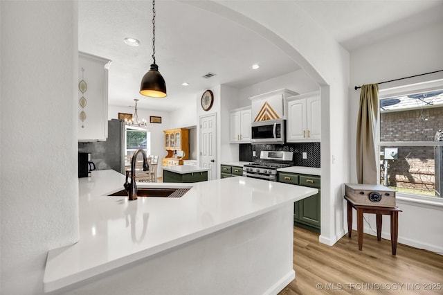 2405 S 13th St, Broken Arrow, OK 74012 - kitchen featuring appliances with stainless steel finishes, a sink, backsplash, arched walkways, and white cabinetry