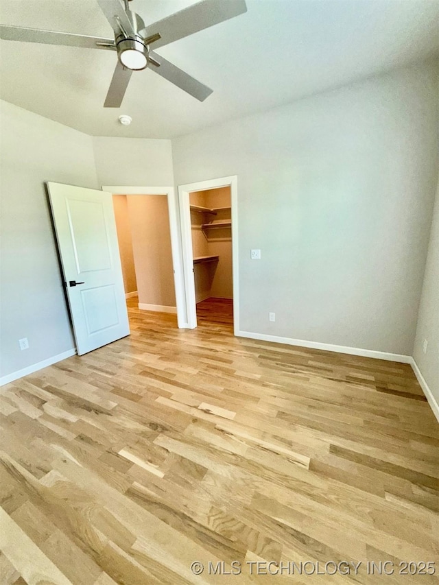 14503 E 80th St N, Owasso, OK 74055 - unfurnished bedroom with a walk in closet, light wood-style floors, baseboards, a ceiling fan, and a closet