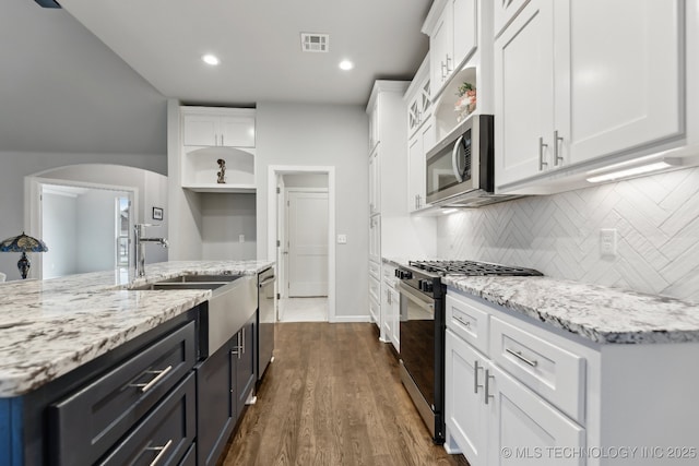 23012 E 104th St S, Broken Arrow, OK 74014 - kitchen with stainless steel appliances, white cabinetry, a sink, arched walkways, and recessed lighting