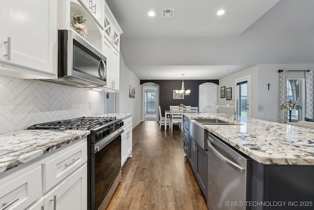 23012 E 104th St S, Broken Arrow, OK 74014 - kitchen with appliances with stainless steel finishes, arched walkways, white cabinets, decorative backsplash, and dark wood-type flooring