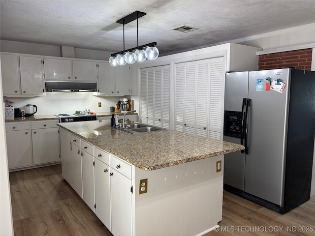 1113 S Meadow Dr, Ardmore, OK 73401 - kitchen with stainless steel refrigerator with ice dispenser, a sink, under cabinet range hood, wood finished floors, and white cabinetry