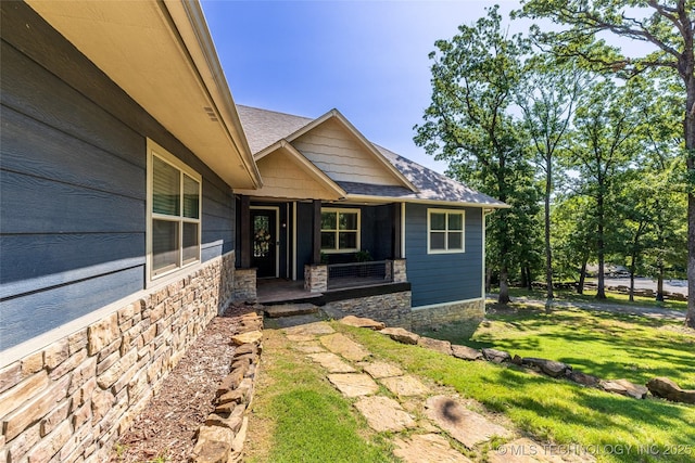 11802 Hickory Ln, Claremore, OK 74017 - doorway to property with a porch, stone siding, a yard, and a shingled roof