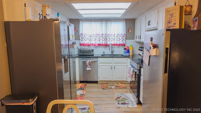 5209 SE Nowata Rd Unit 104B, Bartlesville, OK 74006 - kitchen featuring appliances with stainless steel finishes, a sink, dark countertops, white cabinetry, and a textured ceiling