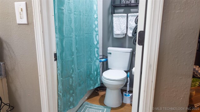 5209 SE Nowata Rd Unit 104B, Bartlesville, OK 74006 - full bathroom with toilet, a textured wall, and a shower with curtain