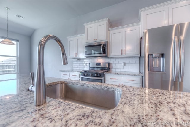 25363 E 87th St S, Broken Arrow, OK 74014 - kitchen with stainless steel appliances, white cabinetry, backsplash, light stone countertops, and hanging light fixtures