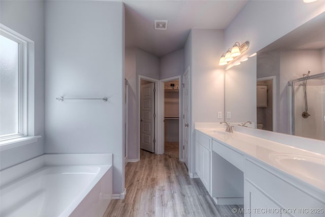 25363 E 87th St S, Broken Arrow, OK 74014 - bathroom featuring a stall shower, double vanity, a garden tub, wood finished floors, and a walk in closet