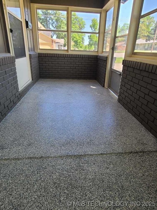 700 S Apple St, Sapulpa, OK 74066 - unfurnished sunroom with brick wall, plenty of natural light, and speckle patterned floor