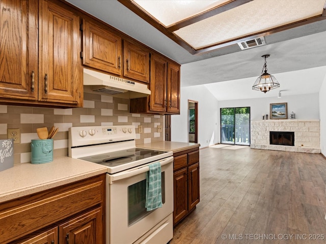 5217 Nowata Rd Unit C204, Bartlesville, OK 74006 - kitchen featuring white range with electric stovetop, under cabinet range hood, light countertops, backsplash, and brown cabinets