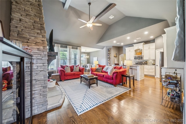 18409 E 50th Pl S, Tulsa, OK 74134 - living area featuring a ceiling fan, light wood finished floors, high vaulted ceiling, a stone fireplace, and a chandelier