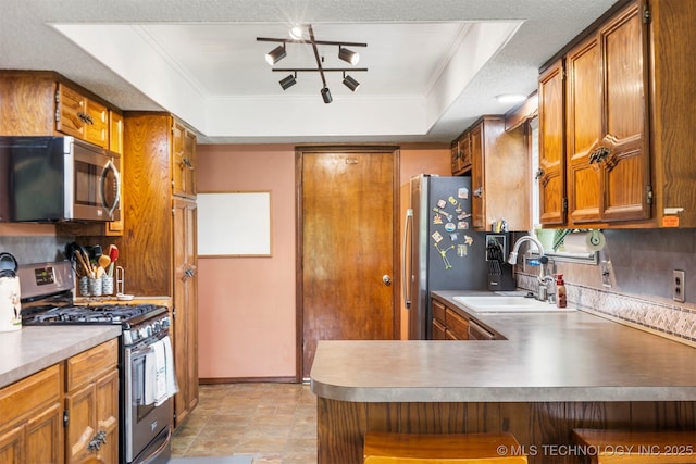 20700 E 420th Rd, Claremore, OK 74017 - kitchen with appliances with stainless steel finishes, a tray ceiling, brown cabinetry, a peninsula, and ornamental molding