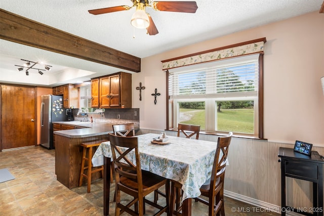 20700 E 420th Rd, Claremore, OK 74017 - dining room featuring plenty of natural light, a textured ceiling, light stone finish floors, ceiling fan, and wainscoting