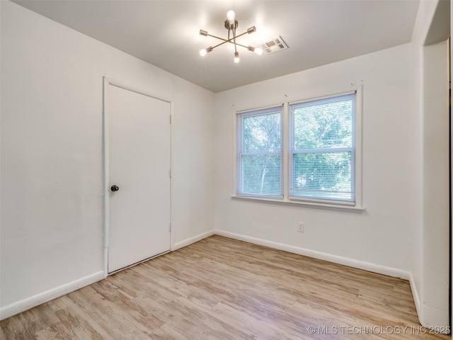 2409 N Urbana Ave, Tulsa, OK 74115 - unfurnished room featuring a chandelier, light wood finished floors, and baseboards