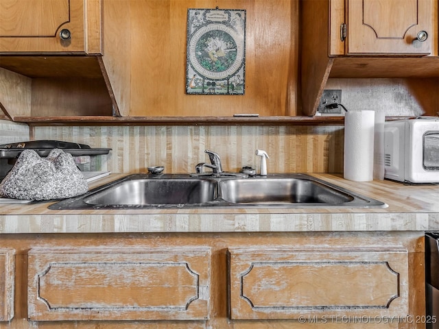 820 N Grand Ave, Okmulgee, OK 74447 - kitchen view of decorative backsplash, a sink, light countertops, and brown cabinets
