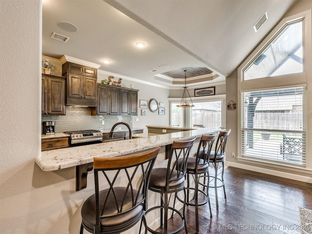 7605 E 82nd Pl, Owasso, OK 74055 - kitchen with gas range, baseboards, a kitchen breakfast bar, dark wood finished floors, and tasteful backsplash