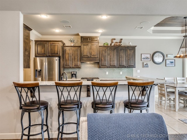 7605 E 82nd Pl, Owasso, OK 74055 - kitchen featuring stainless steel fridge, tasteful backsplash, ornamental molding, dark brown cabinets, and a kitchen bar
