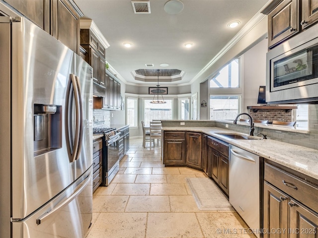 7605 E 82nd Pl, Owasso, OK 74055 - kitchen with stainless steel appliances, a sink, crown molding, a tray ceiling, and decorative backsplash