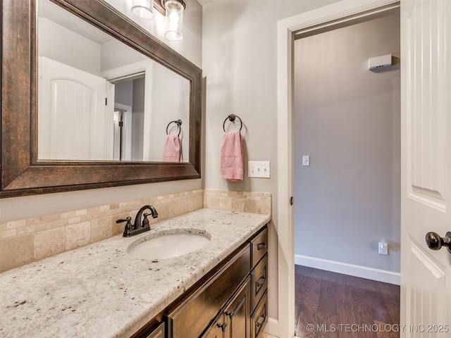 7605 E 82nd Pl, Owasso, OK 74055 - bathroom with baseboards, wood finished floors, vanity, and backsplash