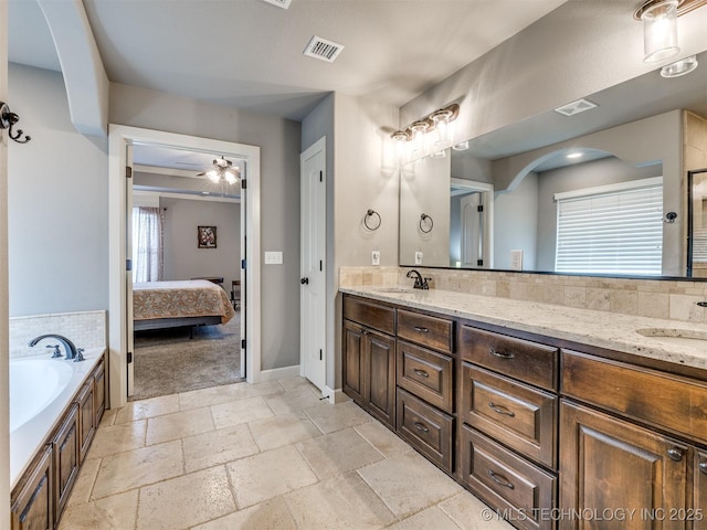 7605 E 82nd Pl, Owasso, OK 74055 - ensuite bathroom featuring double vanity, a garden tub, stone tile floors, and baseboards