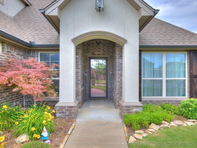 7605 E 82nd Pl, Owasso, OK 74055 - property entrance featuring stucco siding, stone siding, roof with shingles, and brick siding