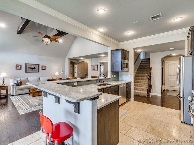 7605 E 82nd Pl, Owasso, OK 74055 - kitchen with a sink, arched walkways, a peninsula, open floor plan, and light stone counters