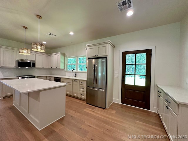 12443 Longboard Loop, Kingston, OK 73439 - kitchen with appliances with stainless steel finishes, a sink, light wood-type flooring, backsplash, and light countertops