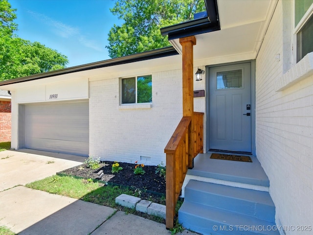 10931 E 4th Pl, Tulsa, OK 74128 - doorway to property with brick siding, a garage, and concrete driveway