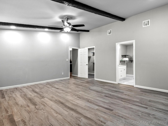 10931 E 4th Pl, Tulsa, OK 74128 - unfurnished bedroom with wood finished floors, baseboards, beamed ceiling, ensuite bathroom, and a walk in closet