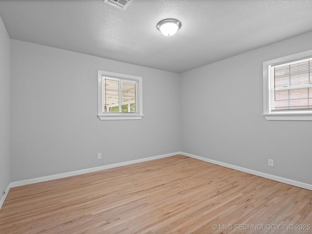 10931 E 4th Pl, Tulsa, OK 74128 - empty room featuring healthy amount of natural light, light wood-style flooring, baseboards, and a textured ceiling