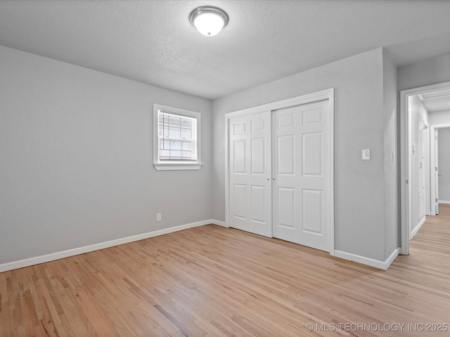 10931 E 4th Pl, Tulsa, OK 74128 - unfurnished bedroom featuring light wood-style floors, baseboards, a closet, and a textured ceiling