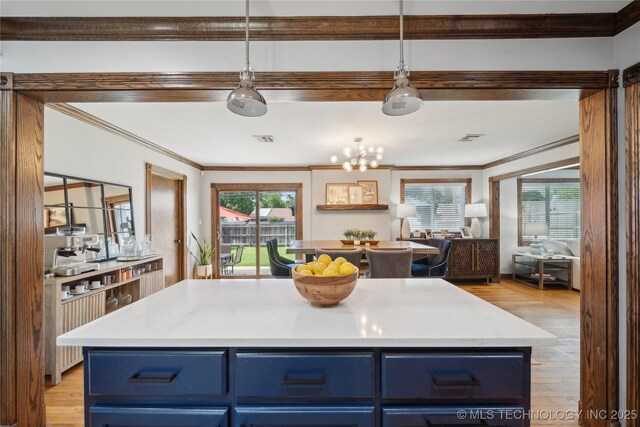 4341 E 56th Pl, Tulsa, OK 74135 - kitchen with blue cabinetry, ornamental molding, plenty of natural light, a chandelier, and light countertops