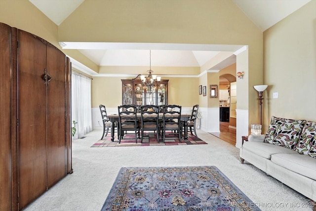 5506 E 110th Pl, Tulsa, OK 74137 - carpeted dining area with arched walkways, a chandelier, high vaulted ceiling, and a wainscoted wall