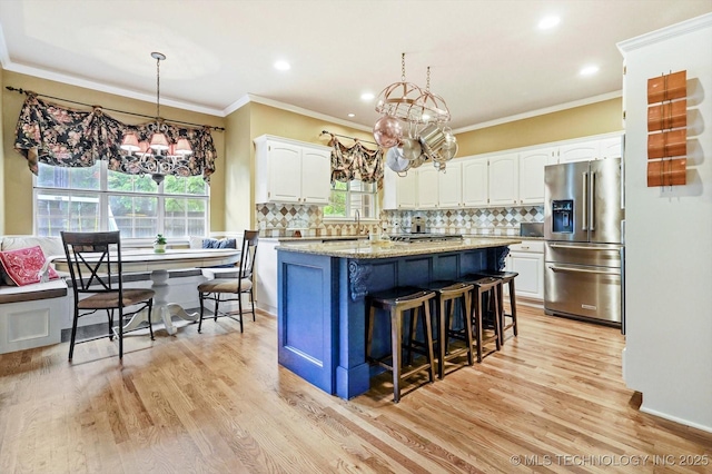 5506 E 110th Pl, Tulsa, OK 74137 - kitchen with stainless steel fridge, a chandelier, white cabinetry, a kitchen island, and light wood-type flooring
