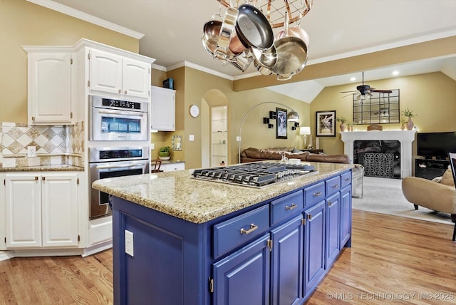 5506 E 110th Pl, Tulsa, OK 74137 - kitchen featuring blue cabinets, appliances with stainless steel finishes, open floor plan, white cabinets, and a fireplace