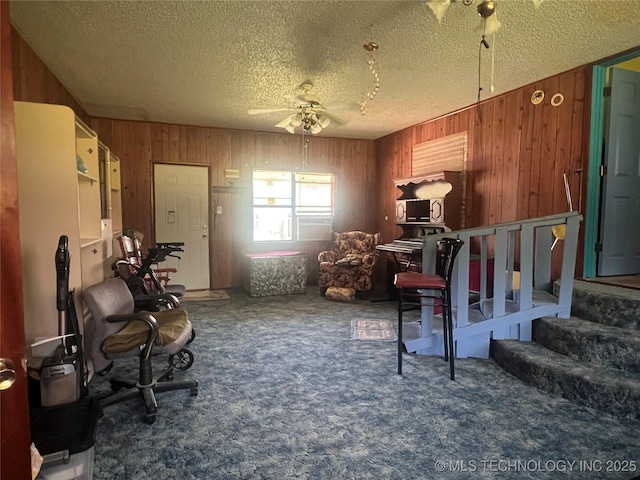 101 N 3rd St, Hartshorne, OK 74547 - living room with a ceiling fan, wood walls, carpet flooring, a textured ceiling, and stairs
