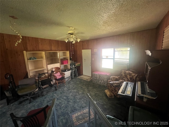 101 N 3rd St, Hartshorne, OK 74547 - living area with wooden walls, a ceiling fan, a textured ceiling, and carpet floors