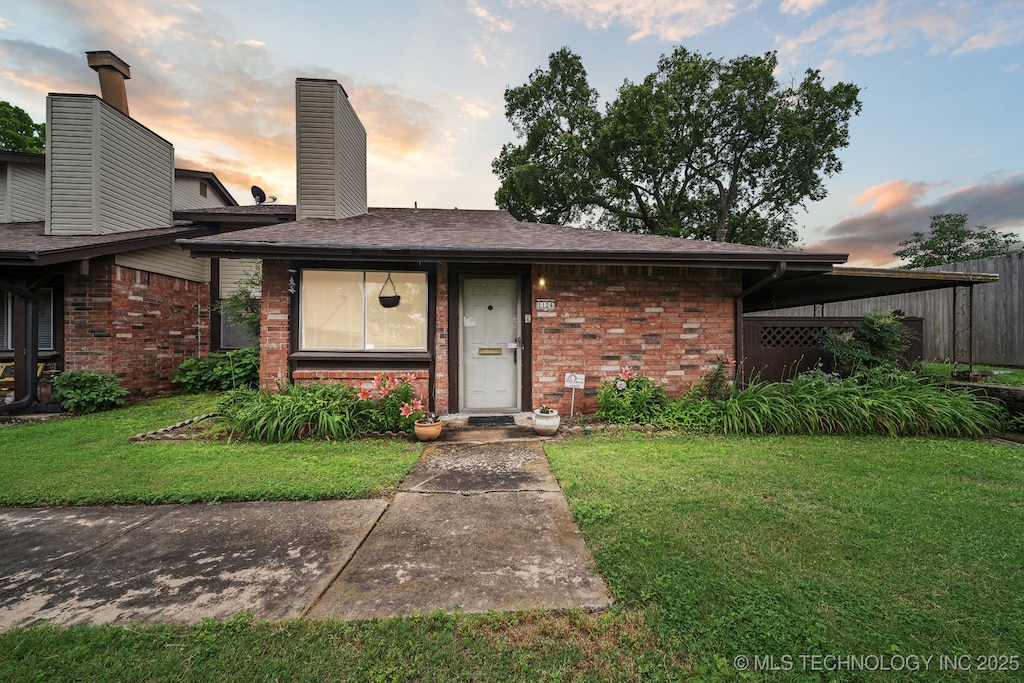 1124 S 110th E Ave Unit 4D, Tulsa, OK 74128 - view of front facade featuring brick siding, a yard, a chimney, and a shingled roof