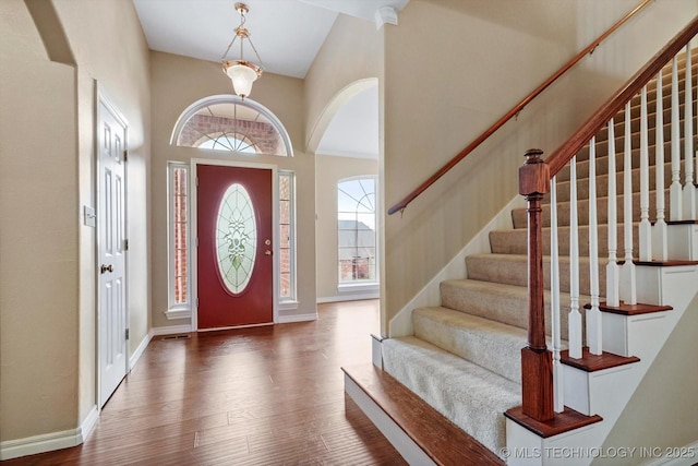 6007 E 76th Ct, Tulsa, OK 74136 - foyer featuring arched walkways, wood finished floors, baseboards, a high ceiling, and stairs