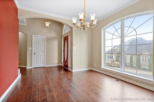 6007 E 76th Ct, Tulsa, OK 74136 - empty room with a chandelier, wood finished floors, baseboards, arched walkways, and crown molding