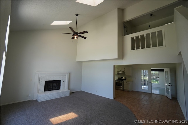 8304 E 124th E Ave, Owasso, OK 74055 - unfurnished living room featuring high vaulted ceiling, a skylight, a fireplace, ceiling fan, and dark colored carpet