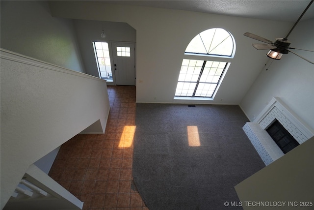 8304 E 124th E Ave, Owasso, OK 74055 - unfurnished living room featuring a ceiling fan, a fireplace, and dark tile patterned flooring